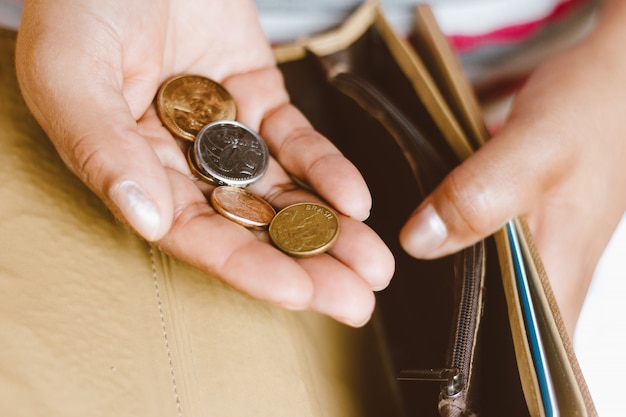 Donna che tiene portafoglio vuoto con alcune monete in sua mano - Concetto di crisi economica - Soldi di risparmio per contabilità finanziaria.
