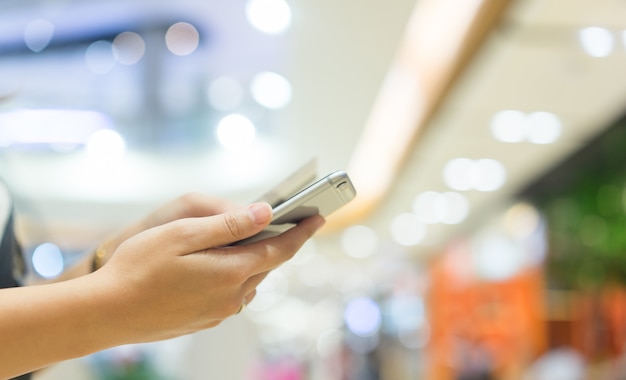 Donna che tiene smartphone con carta di credito per lo shopping online a pagamento