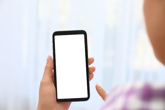 Donna che tiene smartphone con schermo vuoto su sfondo sfocato primo piano delle mani Spazio per il testo