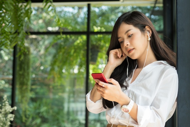 donna che tiene smartphone e ascoltare musica con le cuffie