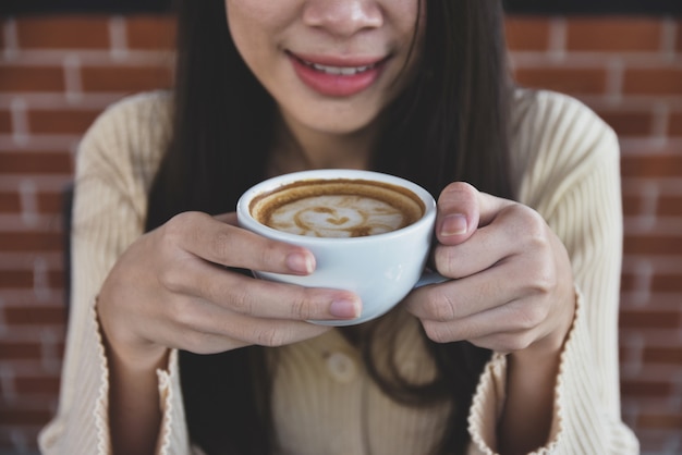 Donna che tiene tazza di caffè al caffè