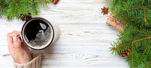 Donna che tiene tazza di caffè caldo sulla tavola di legno rustica. mani in maglione caldo con tazza, mattina d'inverno o concetto di Natale