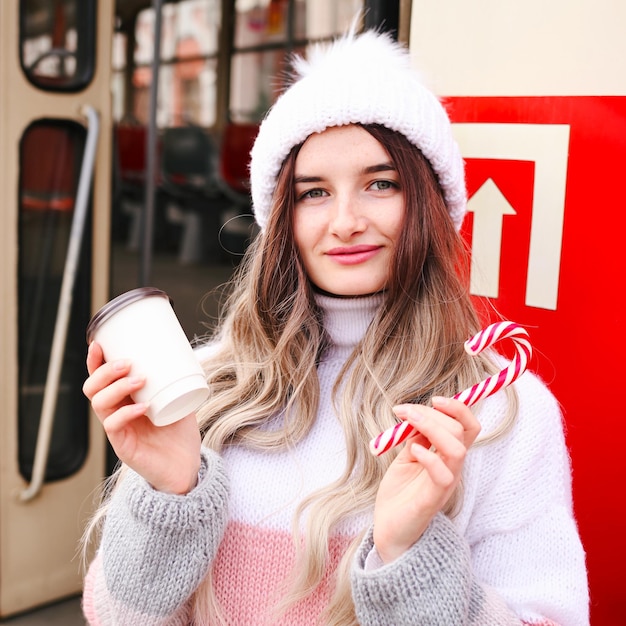 Donna che tiene un bicchiere di carta e beve caffè durante l'attesa del treno