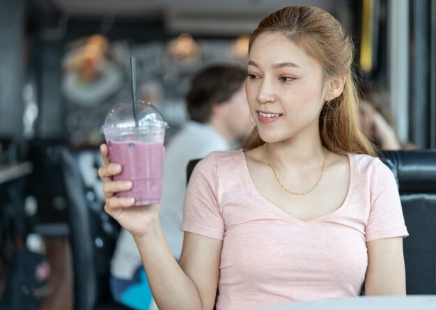 Donna che tiene un bicchiere di frullati di mirtillo nella caffetteria