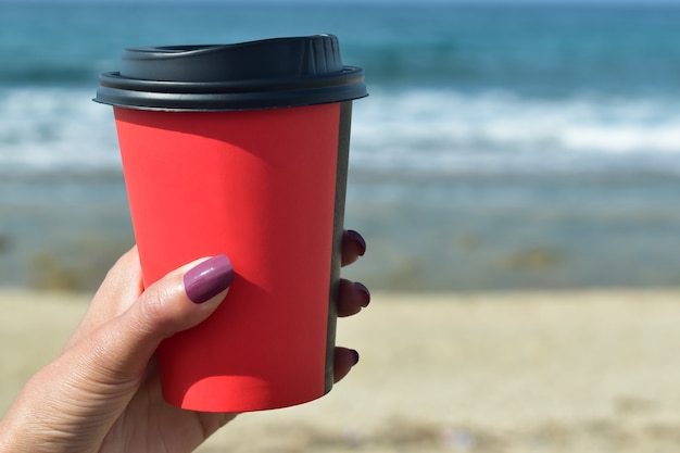 Donna che tiene un caffè contro il mare