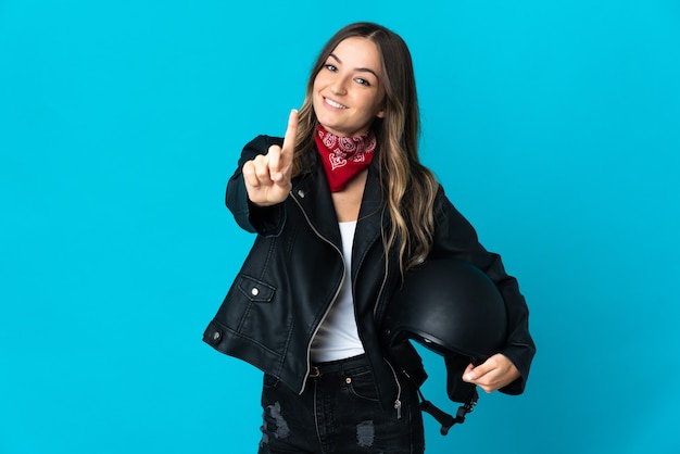 Donna che tiene un casco da motociclista in posa isolata contro il muro bianco