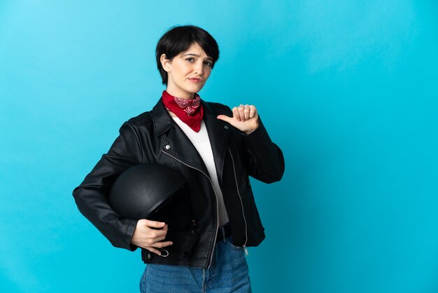 Donna che tiene un casco da motociclista isolato su spazio blu orgoglioso e soddisfatto di sé