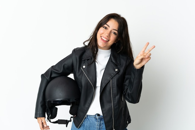 Donna che tiene un casco del motociclo isolato sorridendo e mostrando il segno di vittoria