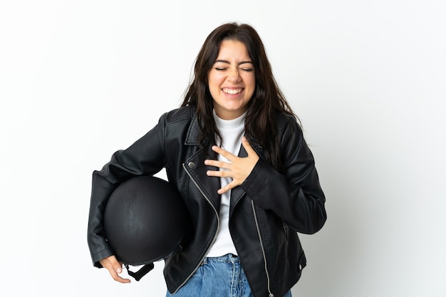 Donna che tiene un casco del motociclo isolato sulla parete bianca che sorride molto