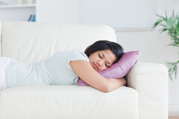 Donna che tiene un cuscino mentre dorme su un divano in un salotto