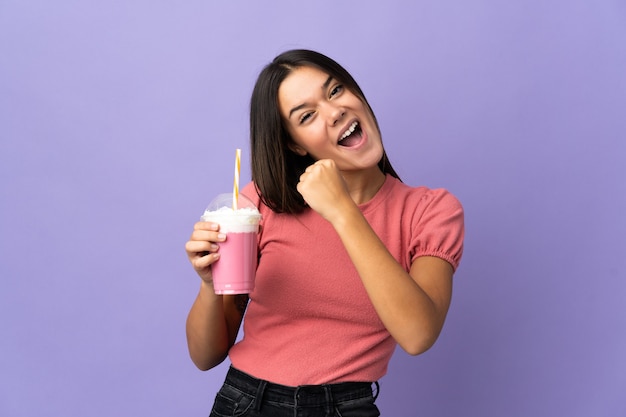 donna che tiene un milkshake alla fragola che celebra una vittoria