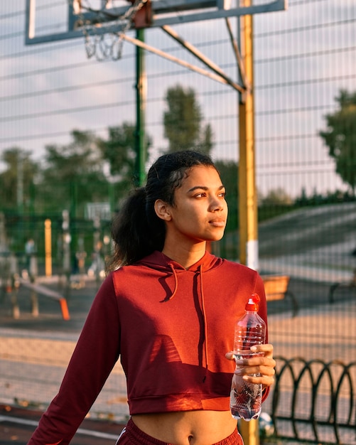 Donna che tiene un pallone da basket e una bottiglia d'acqua