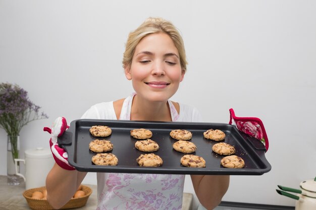 Donna che tiene un vassoio di biscotti con gli occhi chiusi in cucina