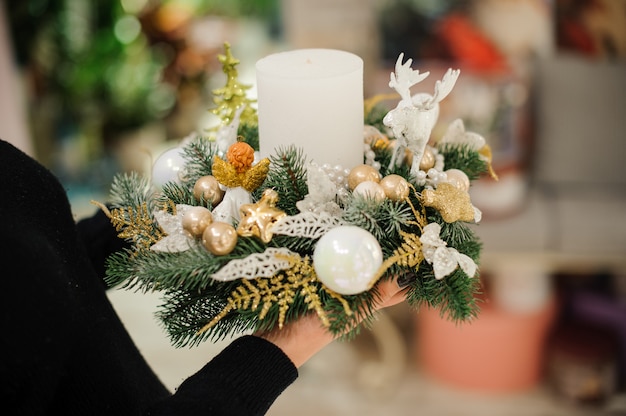 Donna che tiene una composizione di Natale fatta di abete decorato con candele, palline di vetro e cervi