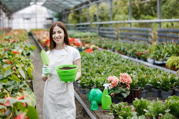 Donna che tiene una pentola e una pala per il trapianto di piante