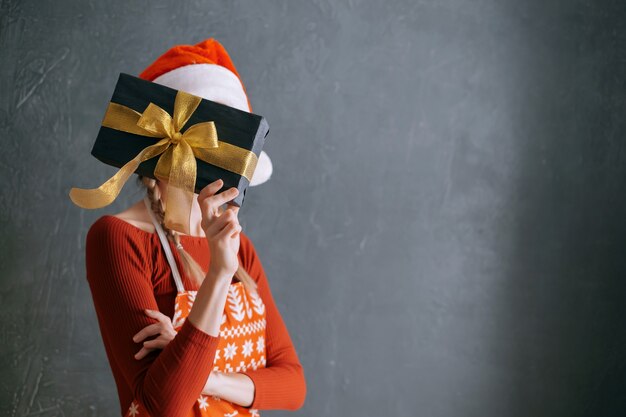 Donna che tiene una scatola con un regalo di Natale tra le mani davanti al viso