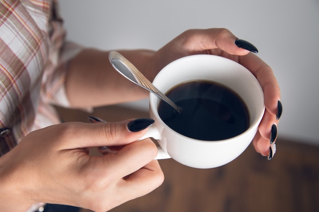 Donna che tiene una tazza di caffè con un cucchiaio