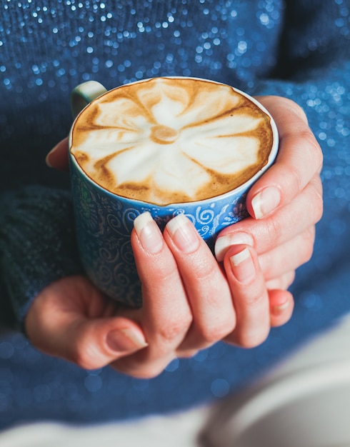 Donna che tiene una tazza di caffè latte con un bellissimo motivo