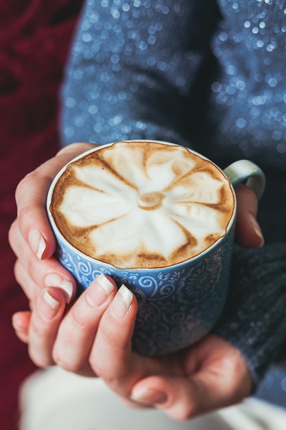 Donna che tiene una tazza di caffè latte con un bellissimo motivo