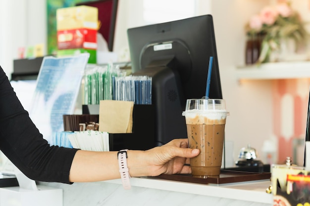 Donna che tiene una tazza di plastica da asporto di caffè ghiacciato nella caffetteria