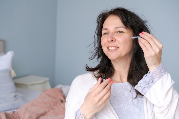 Donna che tocca il contorno occhi laterale pulito con un siero per pipette antibagging