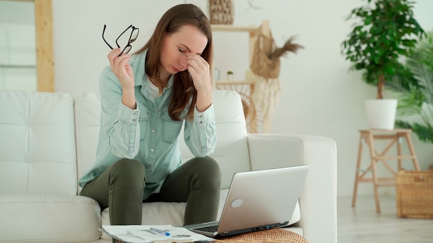 Donna che toglie gli occhiali stanca del lavoro del laptop, problema dopo un lungo utilizzo del laptop