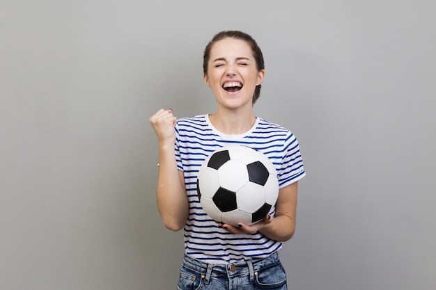 Donna che urla tenendo il pallone da calcio che celebra la vittoria della squadra di calcio preferita nel campionato