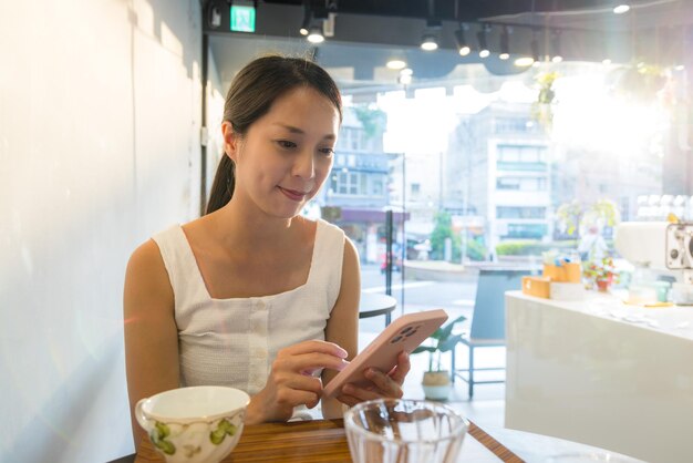 Donna che usa il cellulare al caffè.