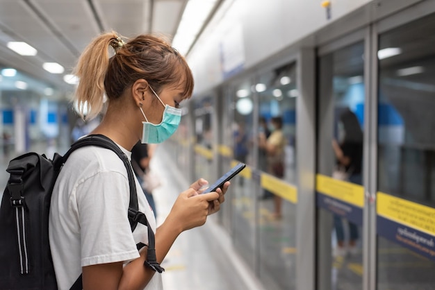 Donna che usa il cellulare mentre è in piedi in attesa del treno