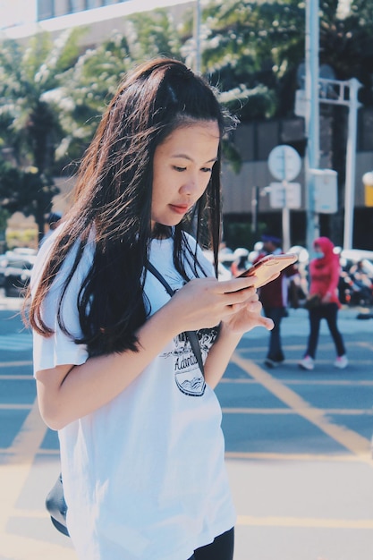 Donna che usa il cellulare mentre è in piedi per strada