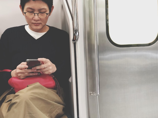 Donna che usa il cellulare mentre è seduta sul treno
