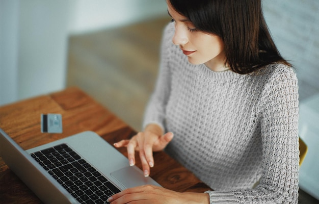 Donna che usa il portatile con carta di credito per fare acquisti online sul tavolo