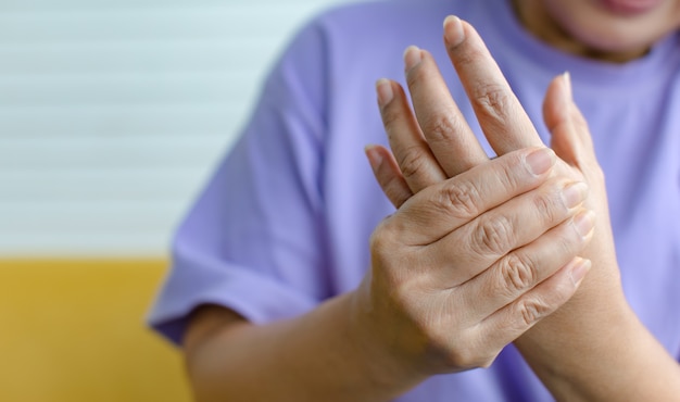 Donna che usa la mano per tenere l'altro sul palmo della mano con dolore, dolore e formicolio. Concetto di sindrome di Guillain barre e malattia delle mani insensibili.