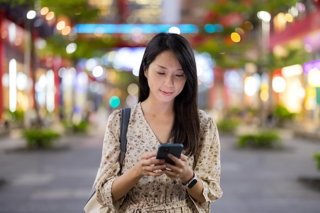 Donna che usa lo smartphone a Taipei di notte