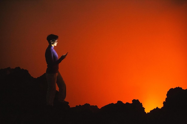 Donna che usa lo smartphone contro il cielo arancione