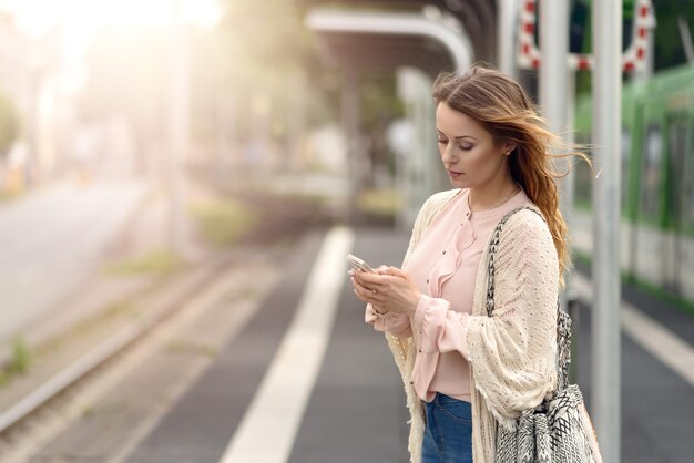 Donna che usa lo smartphone in stazione