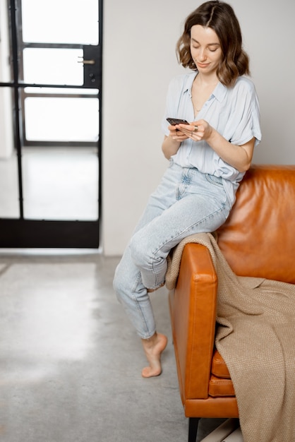 Donna che usa lo smartphone mentre è seduta sul divano
