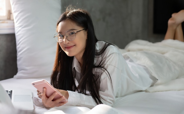 Donna che usa lo smartphone sul suo letto