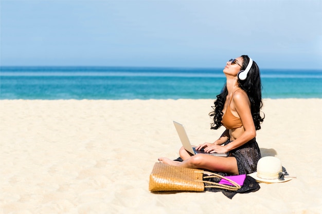 donna che utilizza computer portatile su una spiaggia