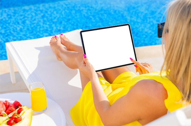 Donna che utilizza computer tablet in piscina mockup schermo vuoto