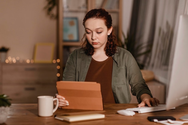 Donna che utilizza il suo tablet a casa mentre beve il caffè