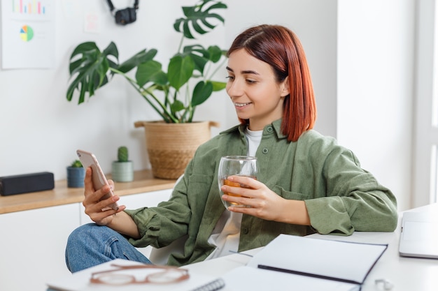 Donna che utilizza il telefono cellulare e beve il tè Concetto di business online o comunicazione home office