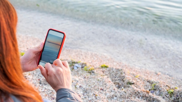Donna che utilizza il telefono cellulare mentre è seduto sulla spiaggia di sabbia