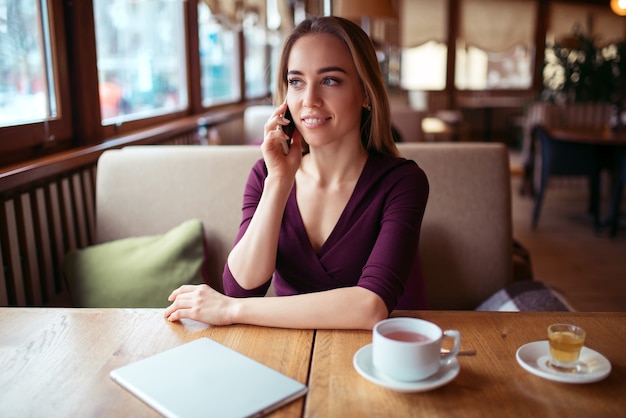 Donna che utilizza il telefono nella caffetteria.