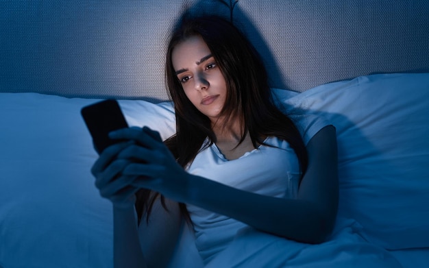 Donna che utilizza smartphone a letto di notte