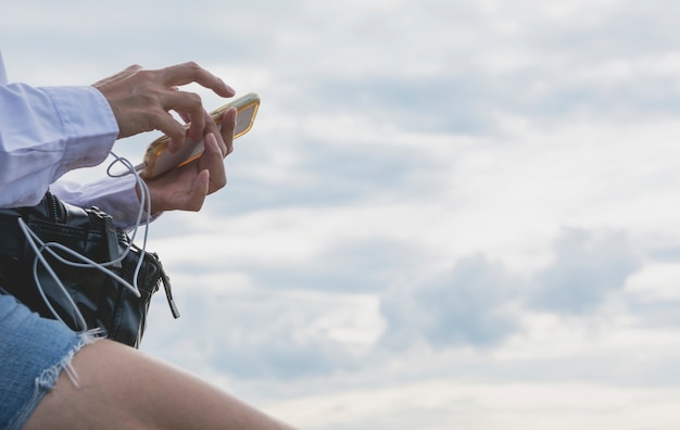 Donna che utilizza smartphone, chat personale e social media sotto il cielo.