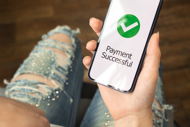 Donna che utilizza smartphone con schermo di successo di pagamento online, concetto di operazioni bancarie e acquisti online, concetto di acquisto foto