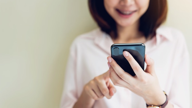 Donna che utilizza smartphone in camera, durante il tempo libero.