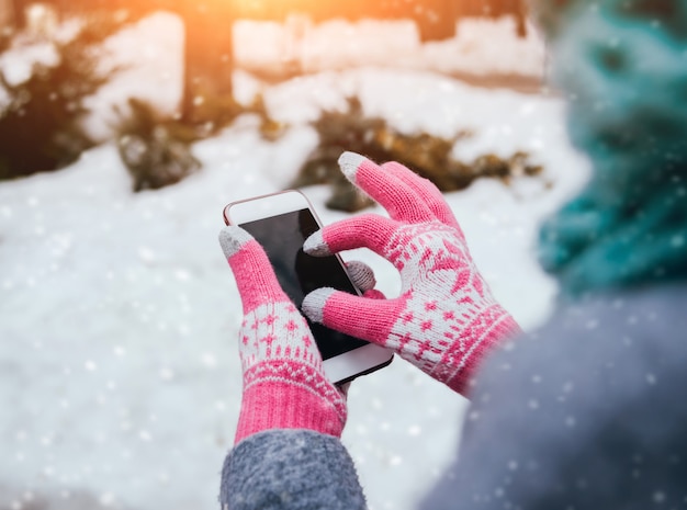 Donna che utilizza smartphone in inverno con guanti per touch screen