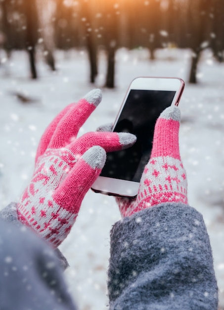 Donna che utilizza smartphone in inverno con guanti per touch screen